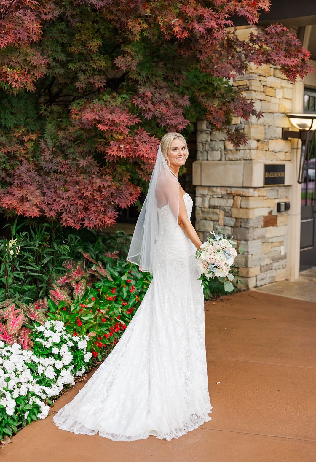 Beautiful bride posing in front of a red Japanese maple tree