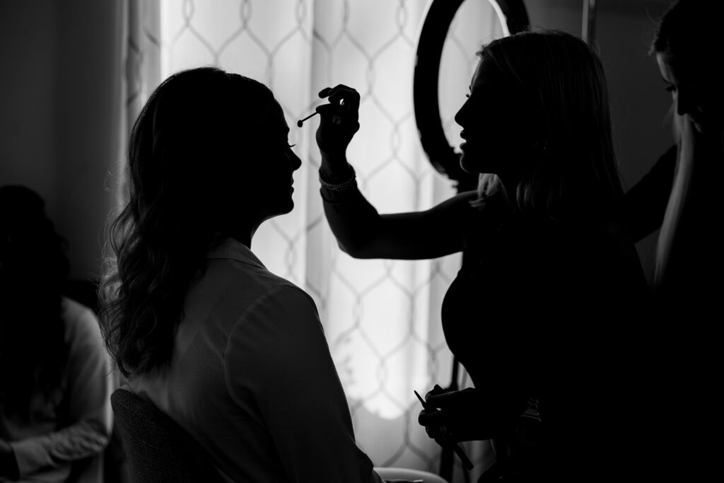 Black and white silhouette of bride having makeup applied