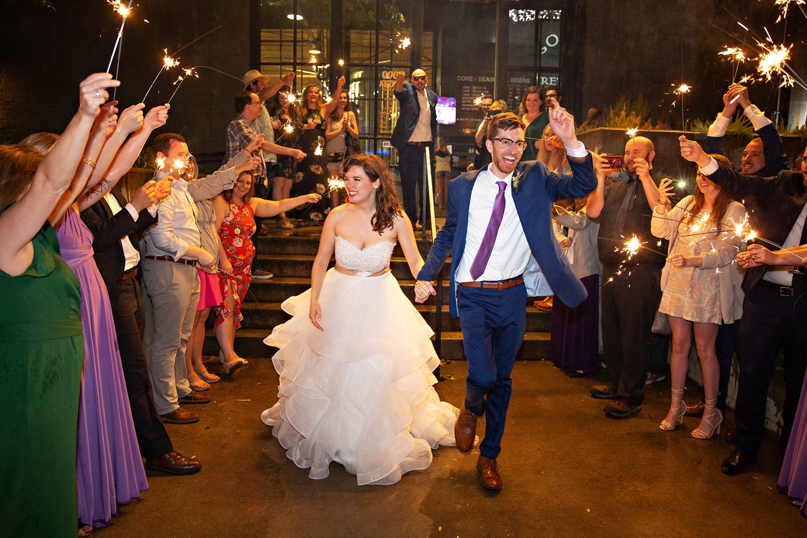 Bride and groom enjoy a sparkler sendoff in the rain.