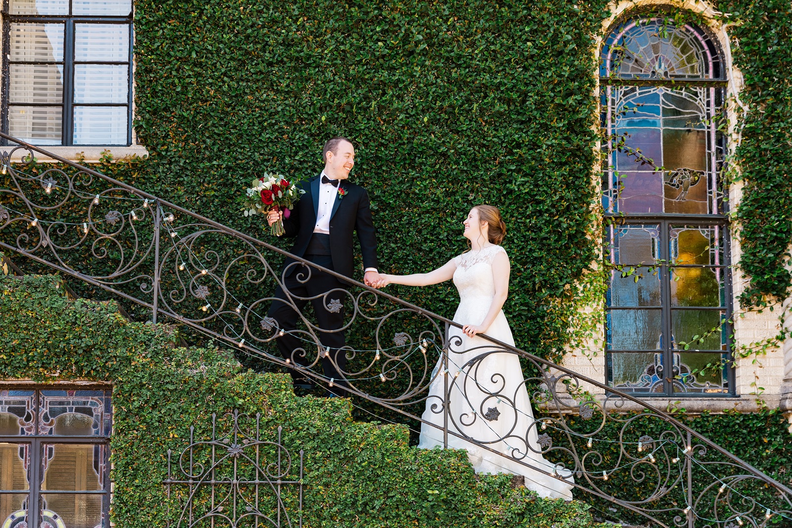 Bride and groom walking up grand stairway holding hands.