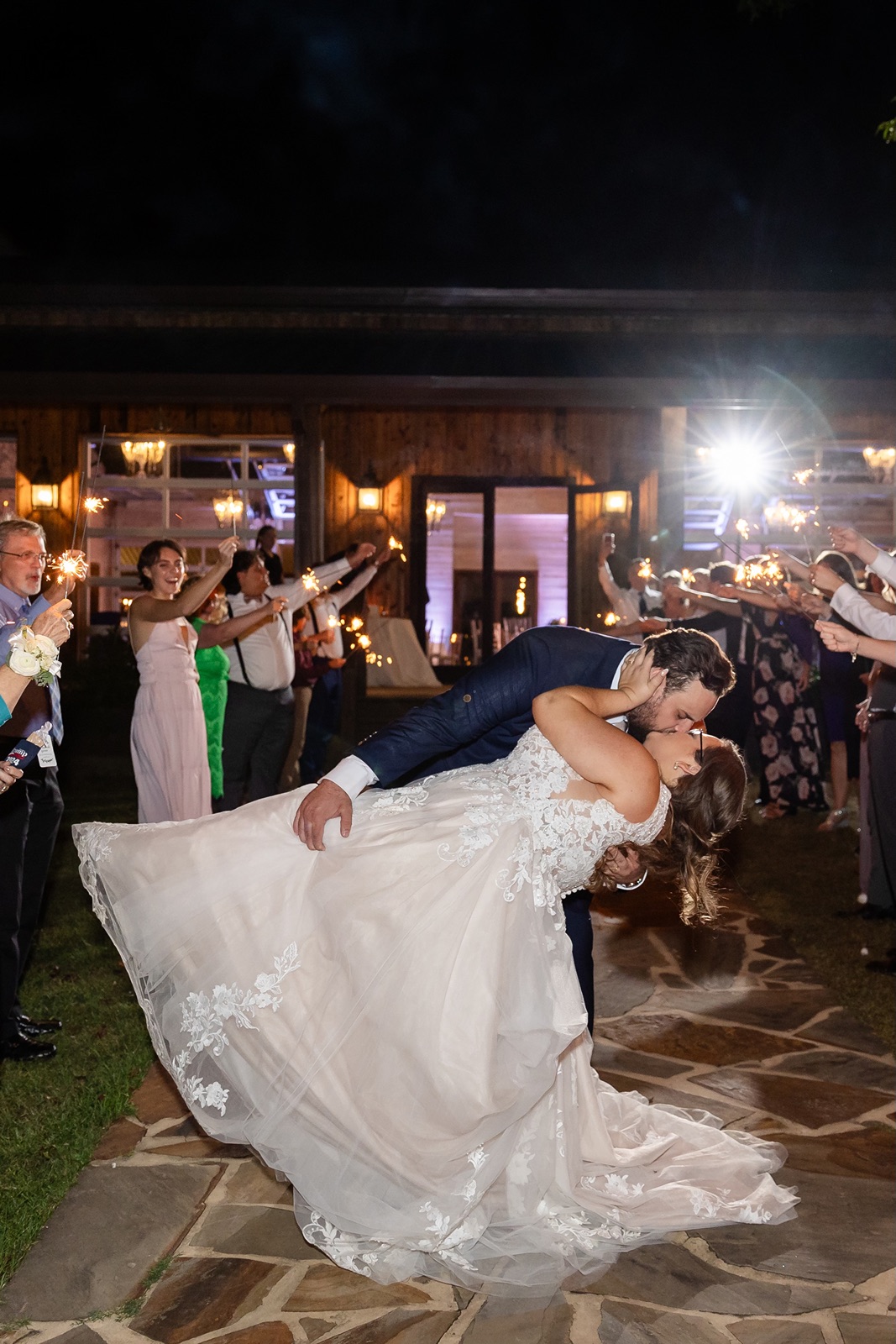 Groom dipping bride during sparkler sendoff.